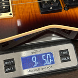 Digital scale displaying weight of a guitar, with a close-up view of the scale and guitar.