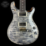 A Prussik electric guitar with a silver and black flamed maple top, shown against a solid black background. The guitar features gold hardware and a white pickguard, with a Tone Shop watermark in the upper left corner.