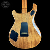 The back of an electric guitar with a natural wood finish and black pickguards, shown against a solid black background with a Tone Shop watermark in the top left corner.