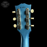 Close-up of a blue guitar headstock with tuning pegs on a black background, featuring 'Tone Shop' branding.