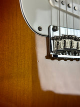 Close-up of a guitar's bridge and headstock on a wooden surface