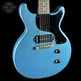 Blue electric guitar with a black pickguard on a black background, featuring 'Tone Shop' branding.