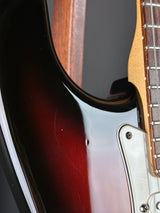 Close-up of a guitar's neck and body with a dark finish.