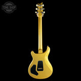 A gold electric guitar shown from the back against a solid black background, with a Tone Shop watermark in the top-left corner.