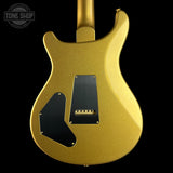 The back of a gold-finish electric guitar body with black pickguard plates, shown against a solid black background. A Tone Shop watermark is visible in the top-left corner.