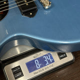 Blue electric guitar on a digital scale displaying weight.