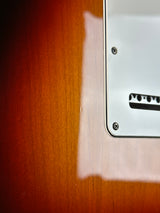 Close-up of a guitar's soundhole with a white pickguard.