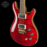 A red flamed maple electric guitar with gold hardware and a gold fingerboard, shown against a solid black background. A Tone Shop watermark is visible in the top-left corner.