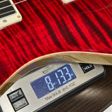 Close-up of a red electric guitar body resting on a digital scale showing 8.13 oz.