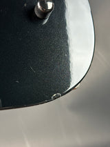 Close-up of a skateboard with a black deck and silver trucks on a gray background