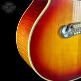 Close-up of a sunburst acoustic guitar with 'Tone Shop' logo in the corner.