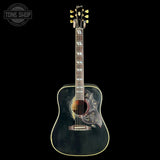 A vintage-style acoustic guitar with a distressed black body, gold hardware, and floral scrollwork inlays on the sides, shown against a solid black background with a Tone Shop watermark in the top-left corner.