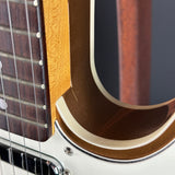 Close-up detail of an electric guitar showing the maple top edge, dark brown fretboard, strings, and a white body with a gold-toned pickguard.