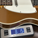 A close-up of a brown and cream electric guitar body resting on a digital kitchen scale displaying 8.15 oz.