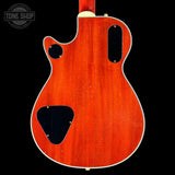 Back view of a red electric guitar with 'Tone Shop' logo in the corner.