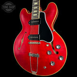 Red electric guitar with a black background, featuring the Tone Shop logo.