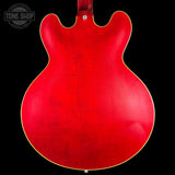 Close-up of a red electric guitar body with 'Tone Shop' logo in the corner.