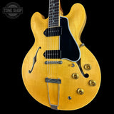 Yellow electric guitar with a black pickguard on a black background, featuring 'Tone Shop' logo.