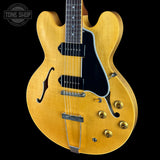 Yellow electric guitar with a black pickguard on a black background, featuring 'Tone Shop' logo.