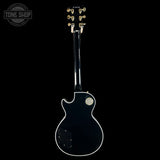 Back view of a black electric guitar with 'Tone Shop' logo.