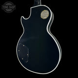 Black electric guitar body with a visible brand logo on a black background