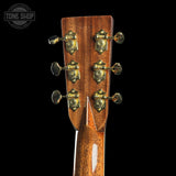 Close-up of a guitar headstock with tuning pegs on a black background, featuring the Tone Shop logo.