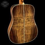 Close-up of a wooden acoustic guitar with a visible brand logo in the corner.