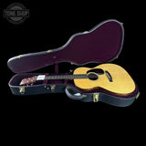 Acoustic guitar in an open case with 'Tone Shop' logo.