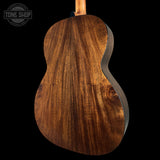 Close-up of a wooden acoustic guitar body with 'Tone Shop' branding.