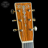Close-up of a guitar headstock with intricate design on a black background