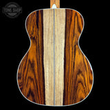 Back view of a wooden acoustic guitar with a visible brand logo in the corner.