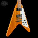 Wooden electric guitar with a white pickguard on a black background, featuring the Tone Shop logo.