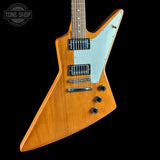 Wooden electric guitar with a white pickguard on a black background, featuring the Tone Shop logo.