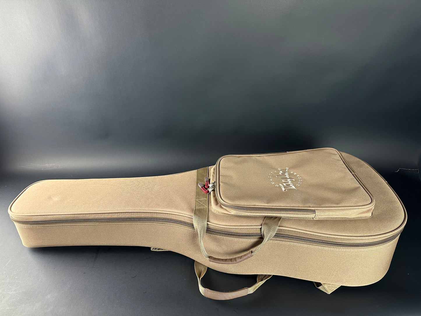 Beige guitar case with brand logo on a dark background