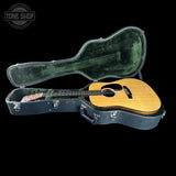 Acoustic guitar in an open case with 'Tone Shop' logo in the corner.