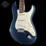 Blue electric guitar with a white pickguard on a black background, featuring the Tone Shop logo.