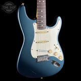 Blue electric guitar with a white pickguard on a black background, featuring the Tone Shop logo.
