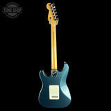 Electric guitar with a blue body and wooden neck on a black background, featuring 'Tone Shop' logo.