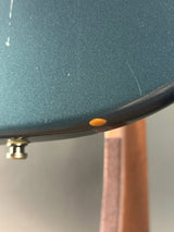 Close-up of a green frying pan with a black handle on a neutral background