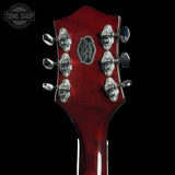 Close-up of a red guitar headstock with tuning pegs on a black background, featuring 'Tone Shop' branding.