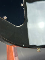 Close-up of a black guitar with visible wear and tear on the body.