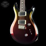 A double-cutaway electric guitar with a glossy dark brown to black sunburst finish, featuring chrome hardware and a dark fretboard, shown against a solid black background with a Tone Shop watermark in the top left corner.