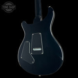 The rear view of a black electric guitar with chrome hardware and a glossy finish, set against a solid black background with a Tone Shop watermark in the top-left corner.