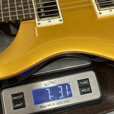 Gold electric guitar on a digital scale displaying weight
