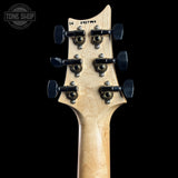 Close-up rear view of an electric guitar headstock made of natural maple wood, featuring six black tuning pegs with gold-toned hardware, set against a solid black background.