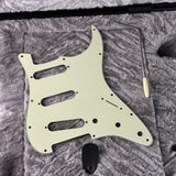 Guitar pickguard with tools on a textured surface
