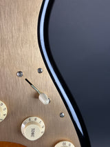 Close-up of a guitar's control knobs and switch on a wooden body.