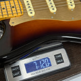Digital scale displaying weight of a guitar on a wooden surface