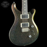 A close-up of a glitter-finish electric guitar body against a black background, with a Tone Shop watermark in the upper left corner.