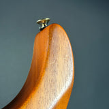 Wooden spoon handle with a metallic knob on a gray background